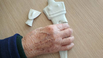 An elderly hand holding a small sculpture